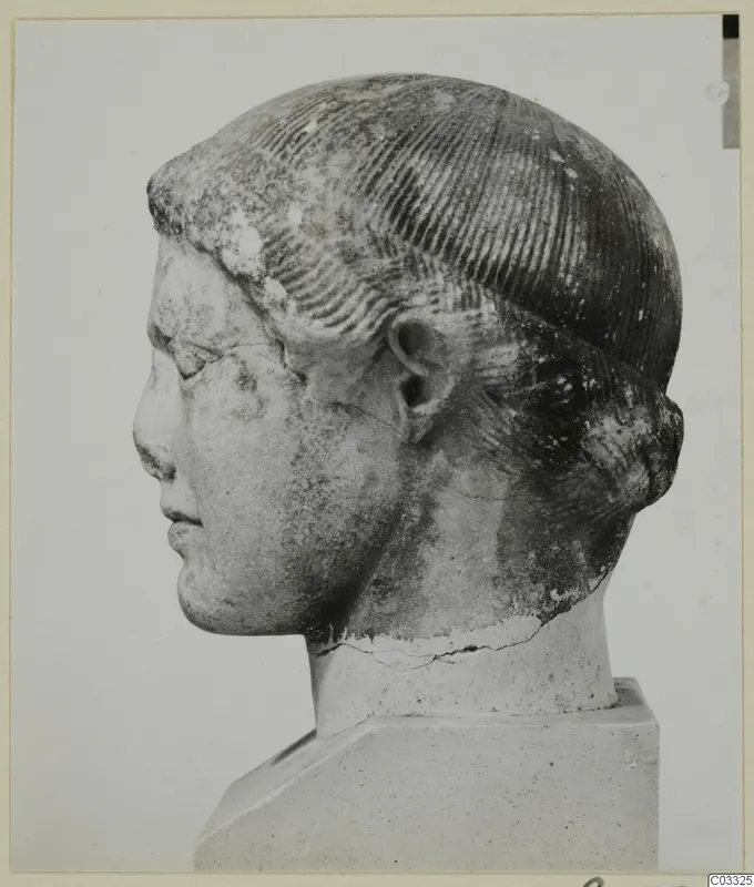 Marble head in left profile, hair with incised parallel lines, standing on a square plinth