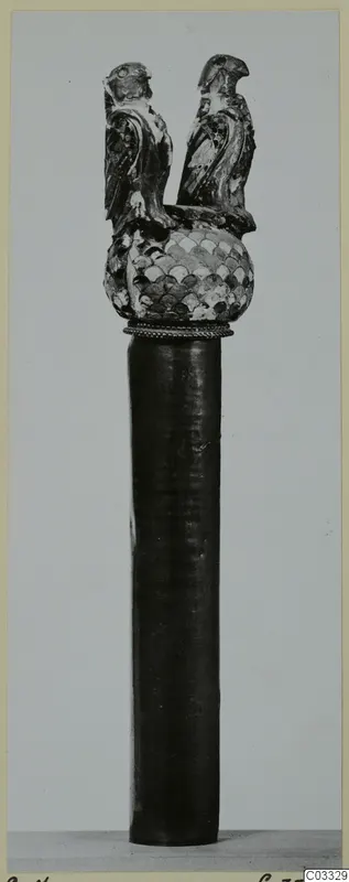Dark cylindrical shaft topped by a scale-patterned knob and two bird figures