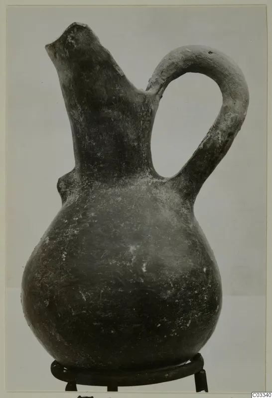 Red Polished III jug with a single loop handle and a broken spout, standing on a metal stand