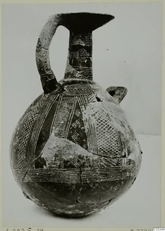 Pottery jug from Lapithos with a tall neck, strap handle and linear decoration on the body