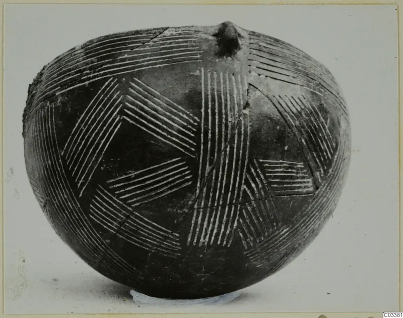 Dark polished vessel with a rounded body, incised hatched pattern filled with white, and a small knob on top