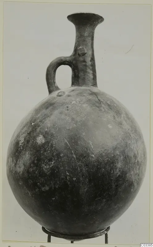 Pottery Red Polished II jug from Lapithos with a globular body, tall flared neck and single loop handle