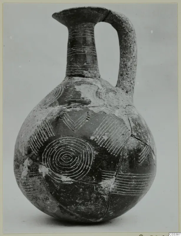 Red Polished II jug with a tall neck, strap handle and bands of lines and concentric circles decorating its body
