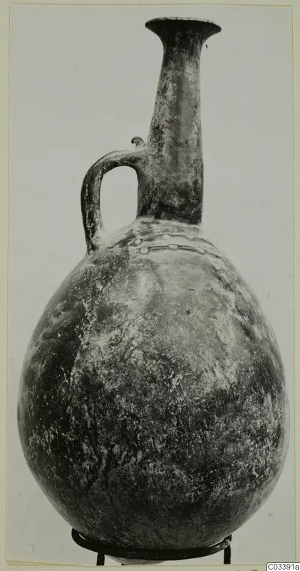 Jug with a tall neck, flared rim, single loop handle and a band of raised ornament on the shoulder, from Lapithos