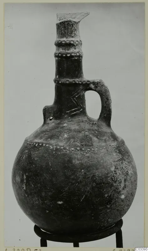 Red Polished III jug from the Vrysi tou Barba tombs at Lapithos, with a single loop handle and dotted neck bands