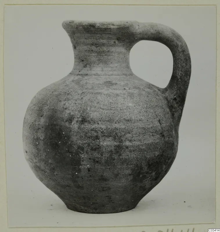 Plain wheel-made jug with a single loop handle and a narrow neck, shown against a light background.