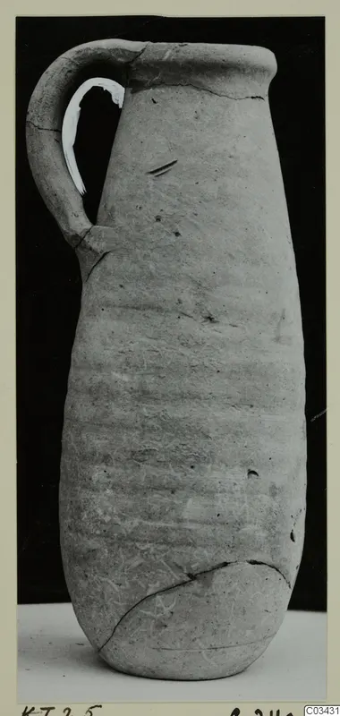 Tall narrow-necked jug with a single strap handle, photographed against a dark background.
