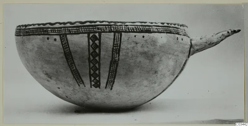 Pottery White Slip Ware bowl with dark painted bands and a long projecting handle