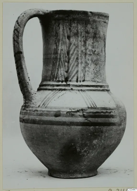 Bichrome painted jug with a tall strap handle and a flaring rim, photographed against a plain background.
