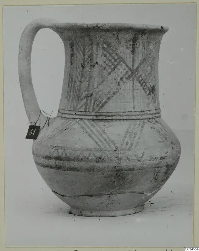 White painted wheel-made jug with a long loop handle and cross-hatched bands of decoration.