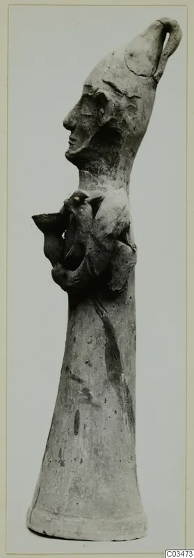Terracotta Minor Plastic 3 from Ayia Irini: a tall clay object with a head in profile and a small clinging figure on its side.