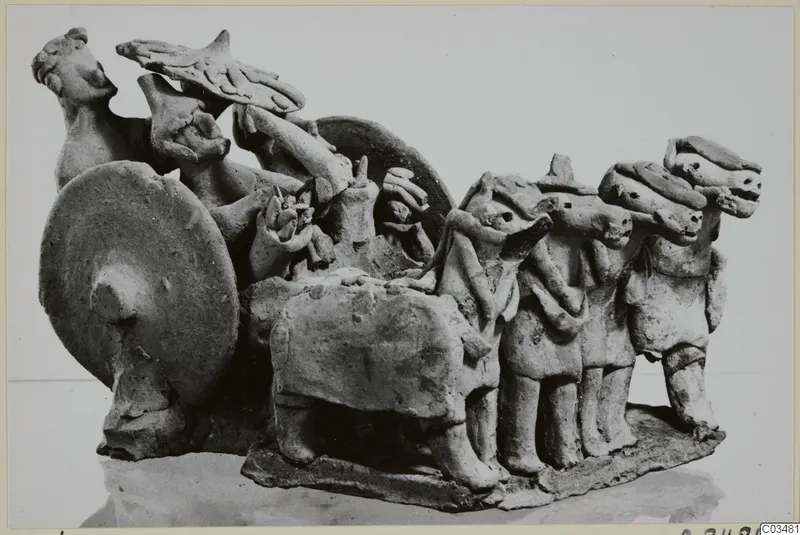 Terracotta group of standing figures and a quadruped beside a large upright disc, on a rectangular base