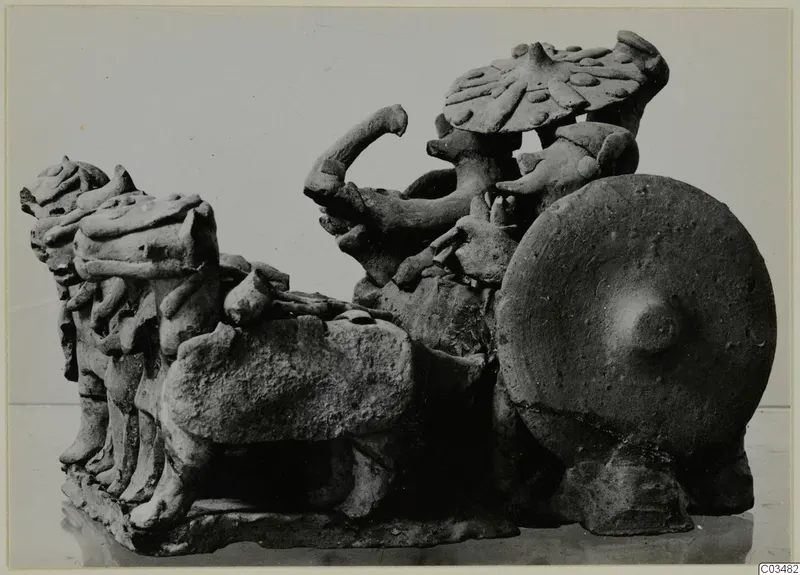 Terracotta group of animal heads and a figure with a large round shield, possibly a chariot with horses