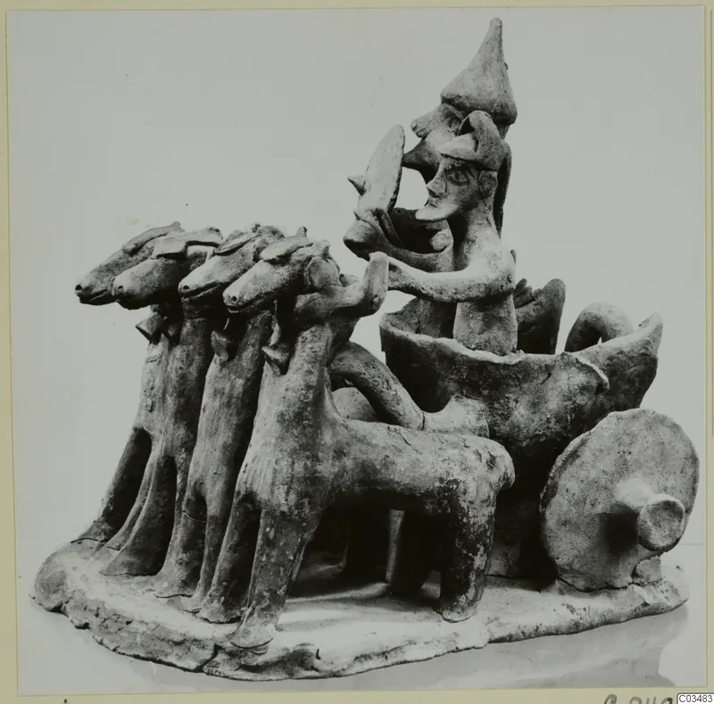 Terracotta model of a vehicle drawn by four animals, with two standing figures, on an oval base