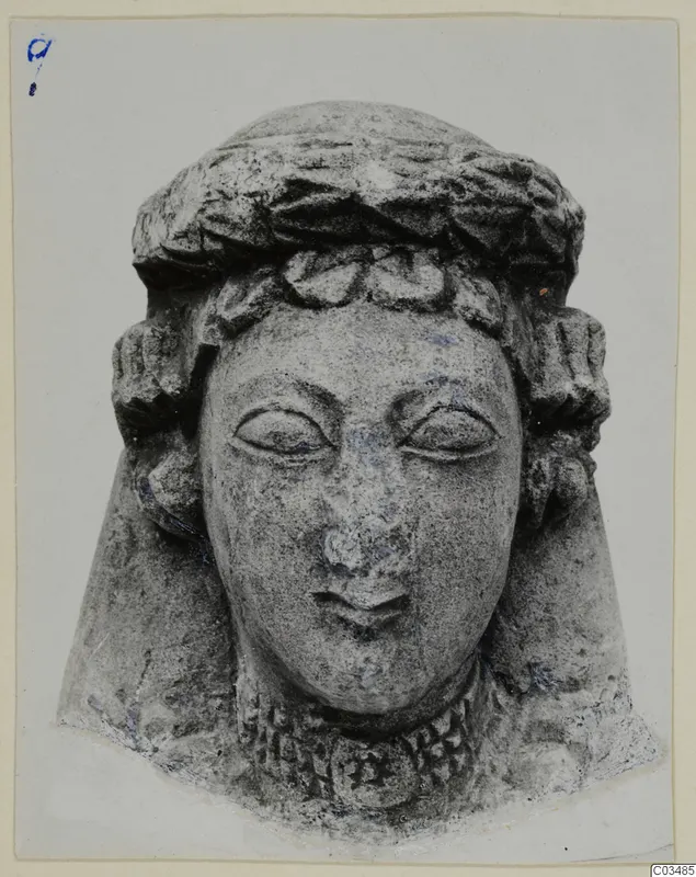 Limestone head sculpture with a wreath-like headband and curled side locks, photographed face-on