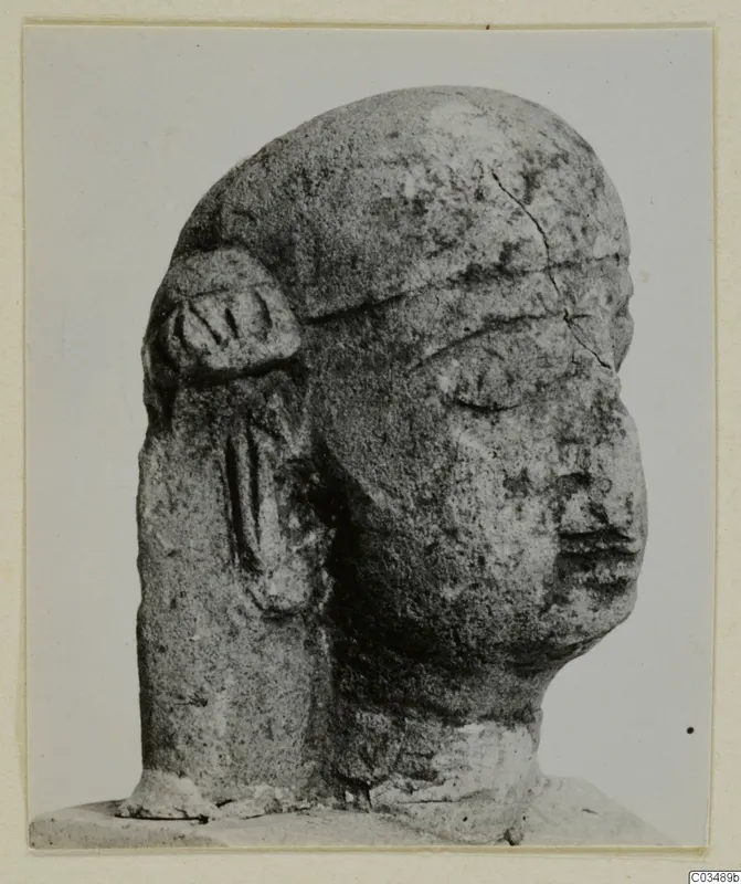 Limestone sculpture of a human head with a worn face and a carved ear-like form on the left side