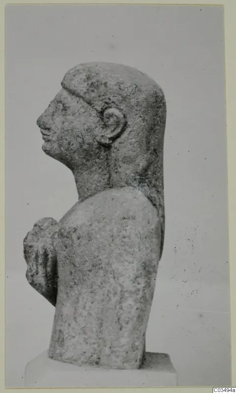 Limestone sculpture of a head and upper body in profile, facing left, with one arm bent up to the chest.