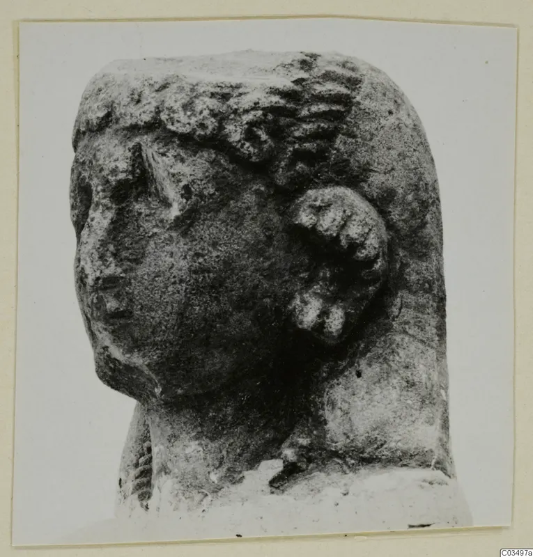Limestone sculpture of a head, photographed in three-quarter view with a worn face on the left.