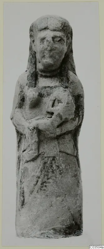 Terracotta figurine of a standing figure with long hair, arms bent across the chest, holding a small rounded object.