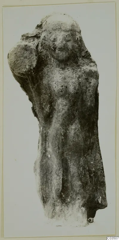 Terracotta figurine of a standing figure with one arm raised to the head and a worn, encrusted surface
