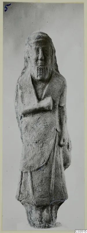 Standing figure with long hair and a short incised beard, one arm folded across the chest, against a plain grey background