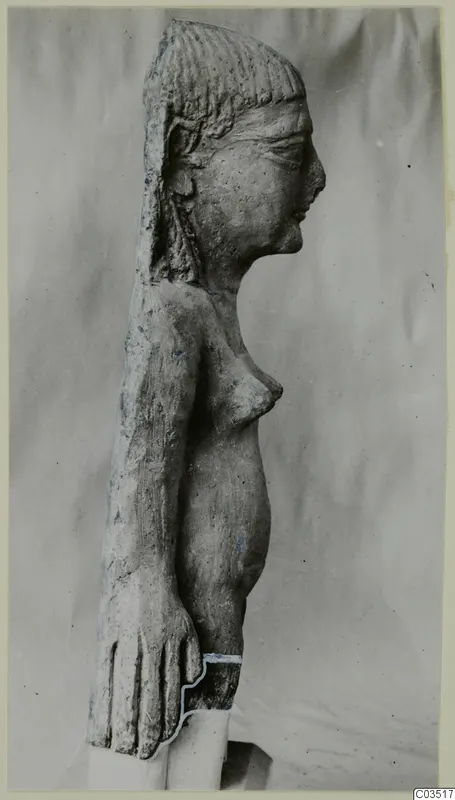 Terracotta figurine of a standing female figure, shown in profile against a grey cloth