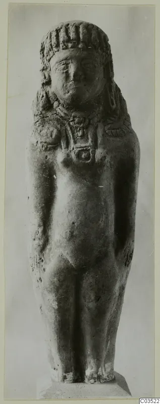 Terracotta standing figurine with a curled headdress and necklace, seen from the front.