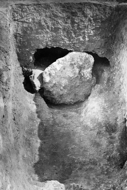 Tomb 8 at Stylli: a large stone blocking the doorway of a tomb cut into an excavation trench.