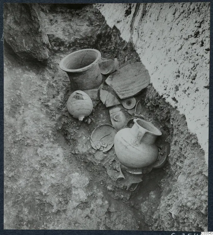 Pottery vessels and loose sherds lying in situ in an excavated trench at Stylli