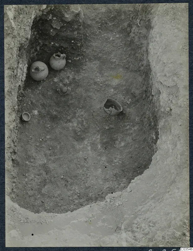 Excavated pit at Stylli with several small pots and a bowl lying in the soil floor