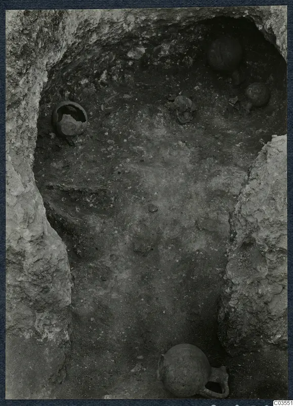 Excavation at Stylli showing several pots and objects lying on the floor of a cut chamber in the rock
