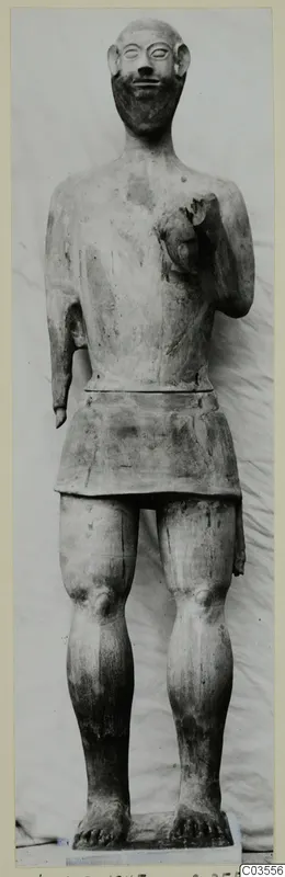 Terracotta statue of a bearded standing figure from Ayia Irini, photographed against a draped light cloth