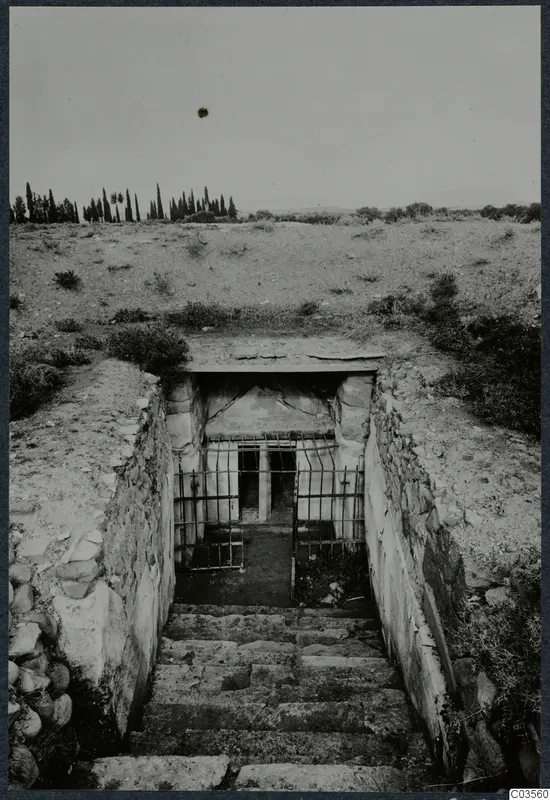 Built tomb entrance at the top of a stone-walled stepped passage, with an iron grille across the doorway