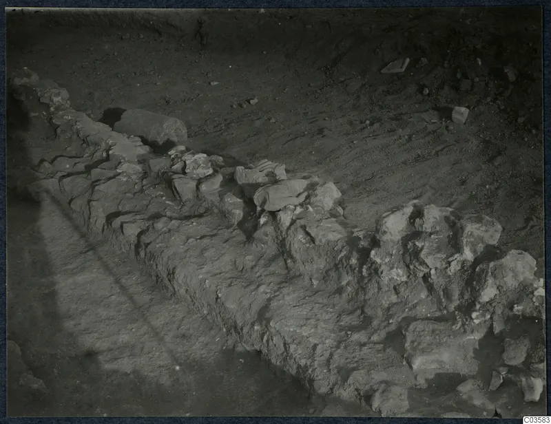 Excavated stone wall foundation running diagonally across bare soil at Soli, Cholades.