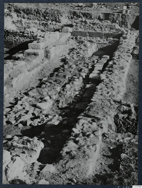 Excavation at Soli showing stone walls, stepped stone blocks and a narrow channel running between rows of stones.