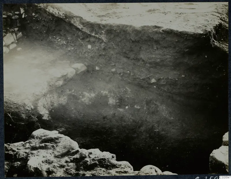 Excavation trench at Soli with a row of pale stones along one side and a layered soil section beyond