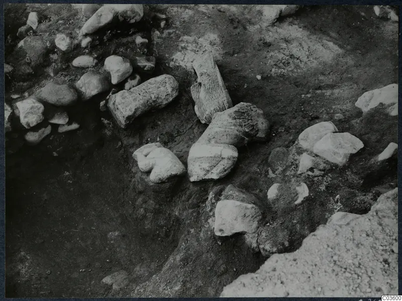 Excavation at Cholades, Soli, showing stone blocks, a cylindrical stone fragment and rubble in a dug trench.