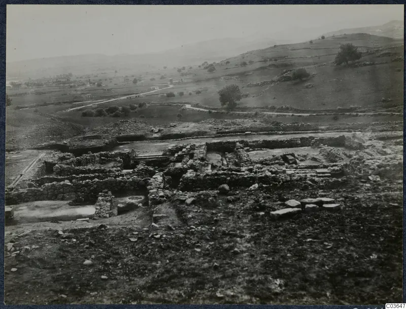 Excavated stone walls and foundations at Soli, Cholades, with fields, hills and a winding road beyond