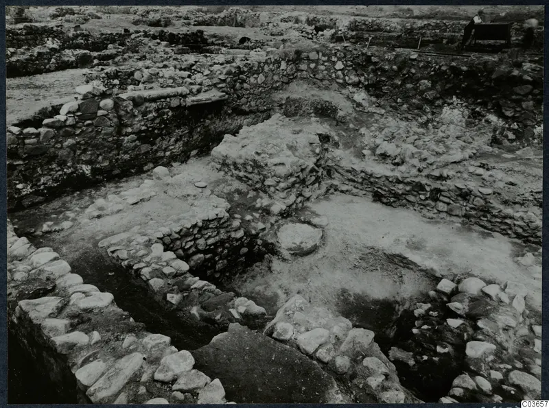 Excavated stone walls and foundations at Soli, Cholades temples, with a standing man by a bench at the top right