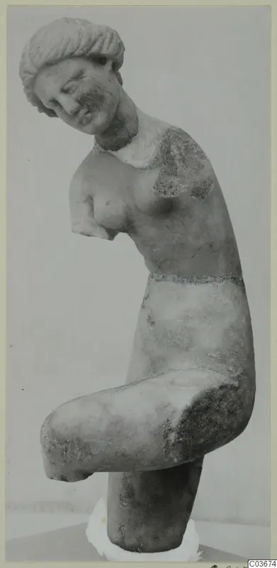Marble statue of a female figure with her head tilted to one side, arms broken off, standing on a white plaster base