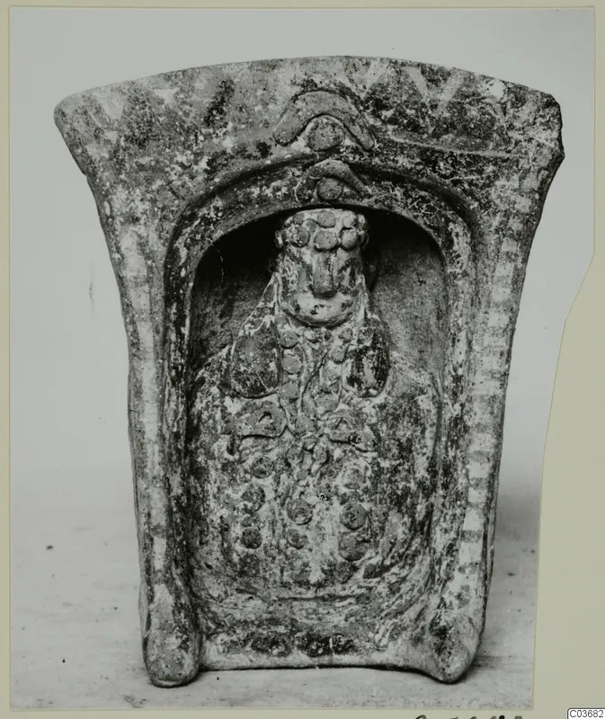 Terracotta object with a relief figure standing in an arched niche, photographed from the front.
