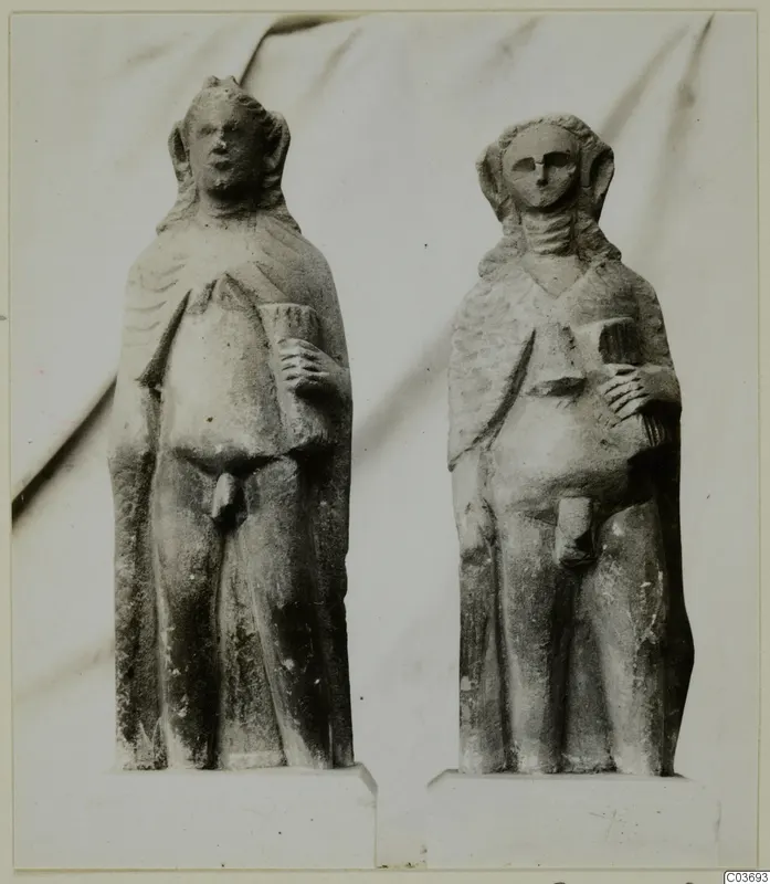 Two limestone standing figurines on plinths, placed side by side.