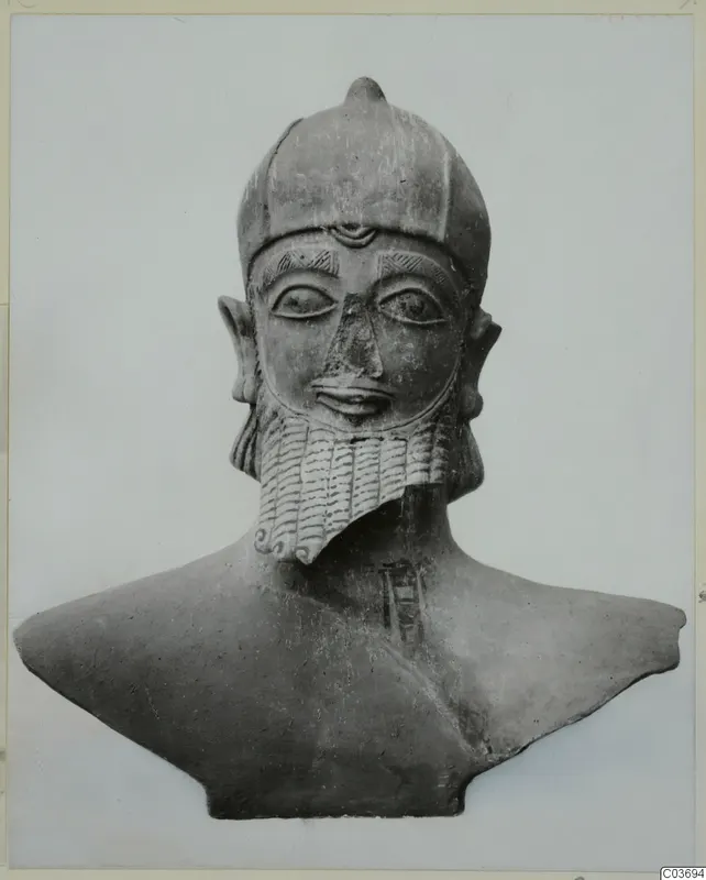 Terracotta bust of a bearded figure in a rounded cap with a small knob on top, shown against a plain background.