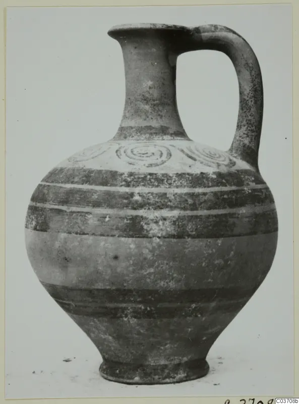 Pottery jug with a single loop handle, a spiral-decorated shoulder and dark painted bands, photographed against a plain background.