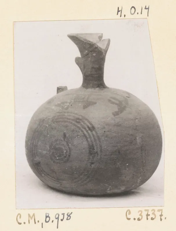 Round painted pottery vessel with a flared spout and dark concentric circle motifs, shown on a photo mount with handwritten labels