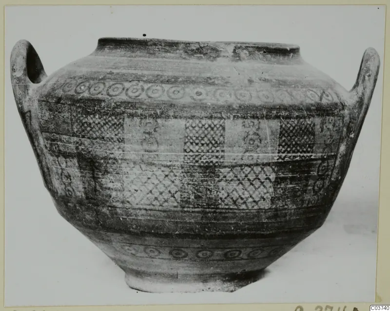 Two-handled Bichrome IV jug with painted bands of rings and cross-hatched panels, photographed against a pale background
