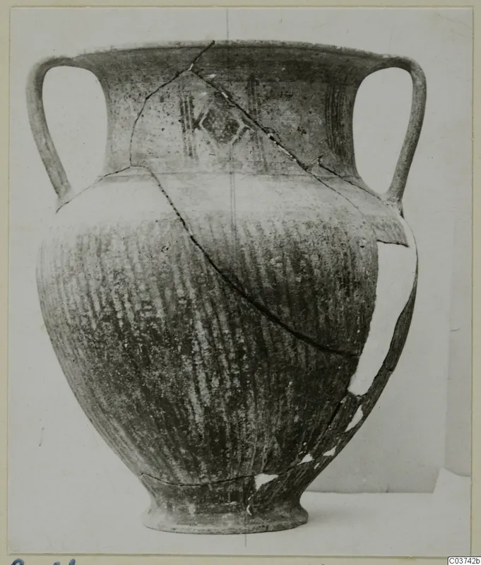 Two-handled jar with painted bands and combed or striated body, shown on a plain background, broken and repaired along cracks.