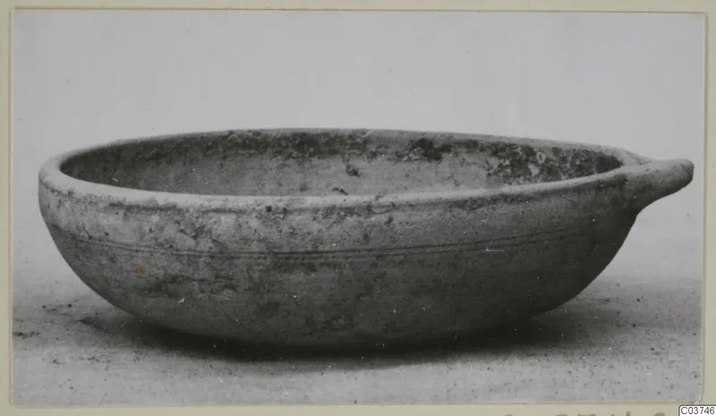 Pottery Plain White IV-V bowl with a single small horizontal handle, seen from the side