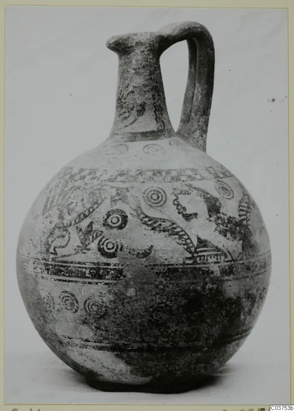 Globular jug with a tall neck, single loop handle and dark painted bands and concentric circles on a pale surface.