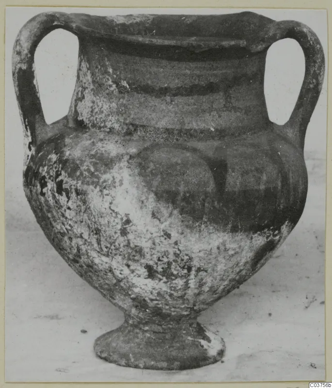 Two-handled pottery vessel with black slip and a pedestal foot, photographed from the front